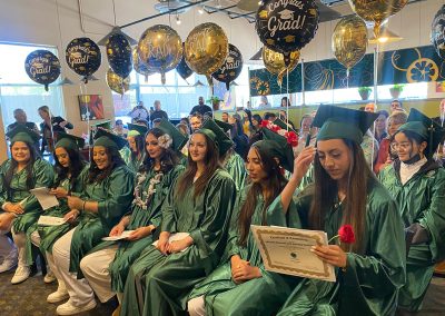 Balloons and decorations and several graduates wearing green gowns and hats at Clinitrack graduation