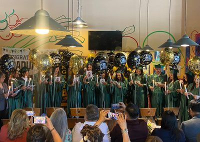 Balloons and decorations and several graduates wearing green gowns and hats at Clinitrack graduation