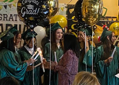 Balloons and decorations and several graduates wearing green gowns and hats at Clinitrack graduation