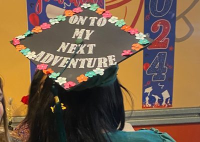 A graduate wearing green gown and hat saying "On to my next adventure" at Clinitrack graduation