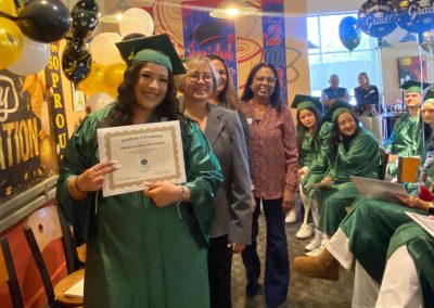 A graduate wearing green gown and hat at Clinitrack graduation